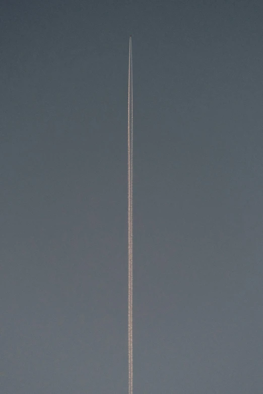 an airplane in a gray sky with a line of contrails