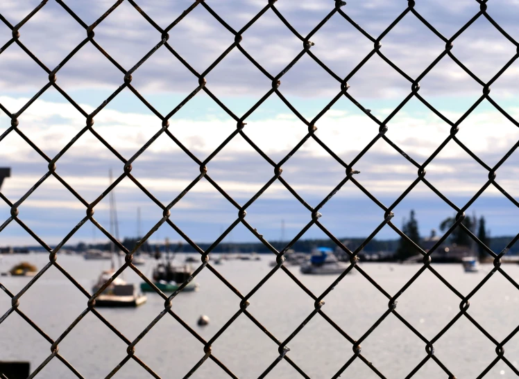 a fence with boats in the distance by some water