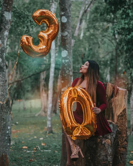 the girl in the woods has her number six balloons attached to the tree