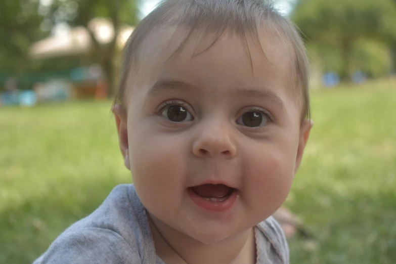 a child wearing a gray shirt smiles at the camera