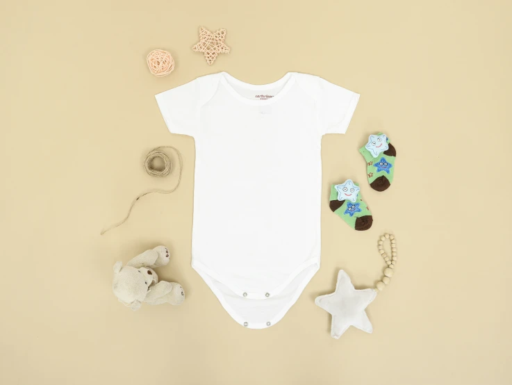 baby boy's onesie and teddy bear on a tan backdrop