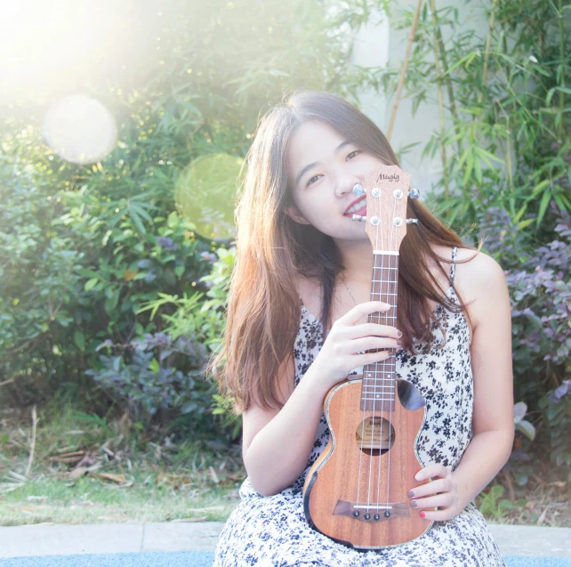a woman holding an acoustic guitar next to some bushes
