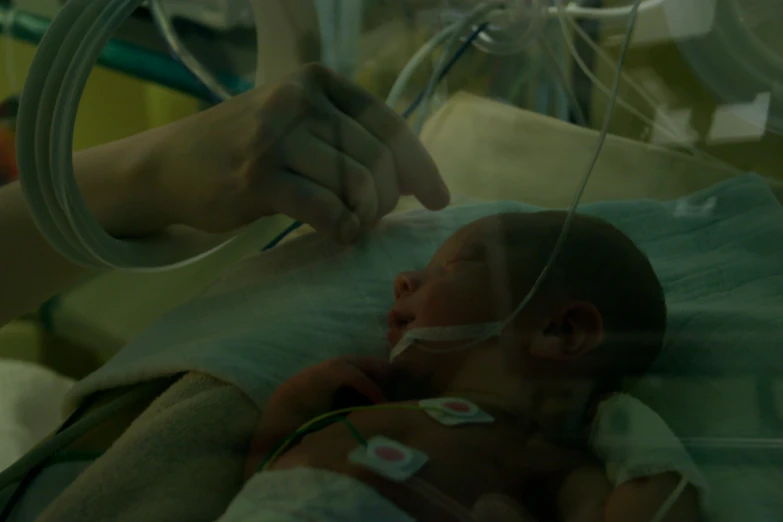 a person holding the hand of a baby on it's shoulder in a hospital