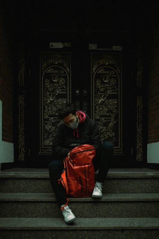 a man sitting on some steps with a red bag