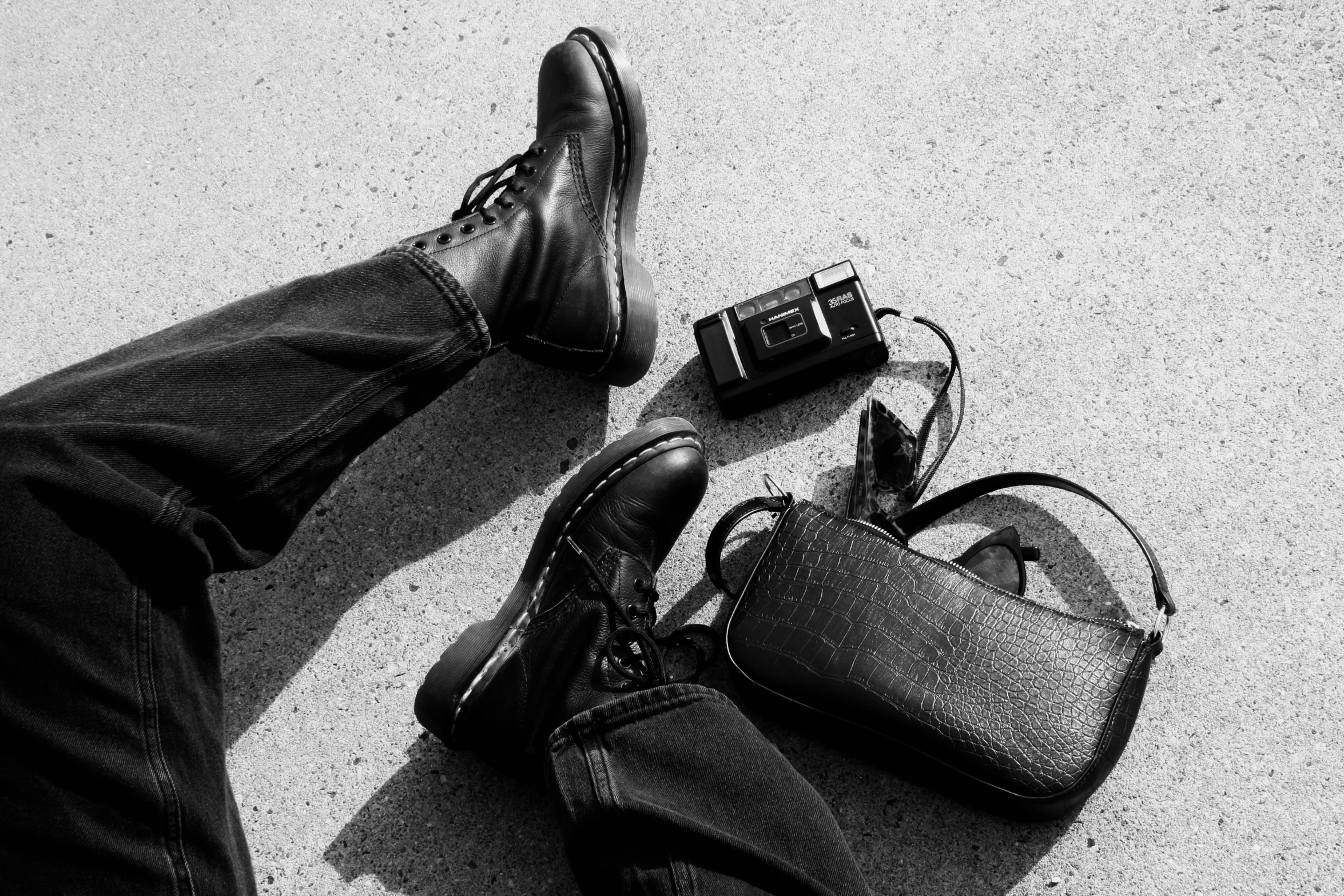 a black and white picture shows someone's legs with their shoes still in the sand