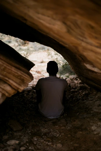 a person sits inside an archway on rocks