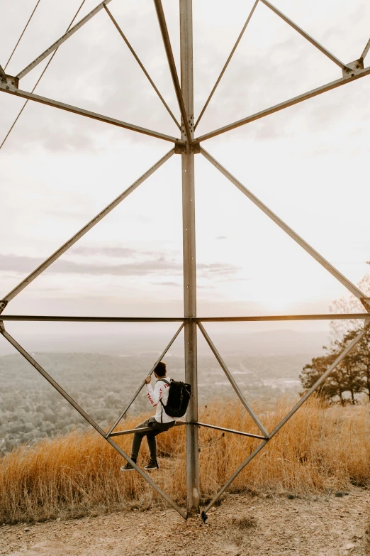 a person with a backpack is holding onto a wire structure