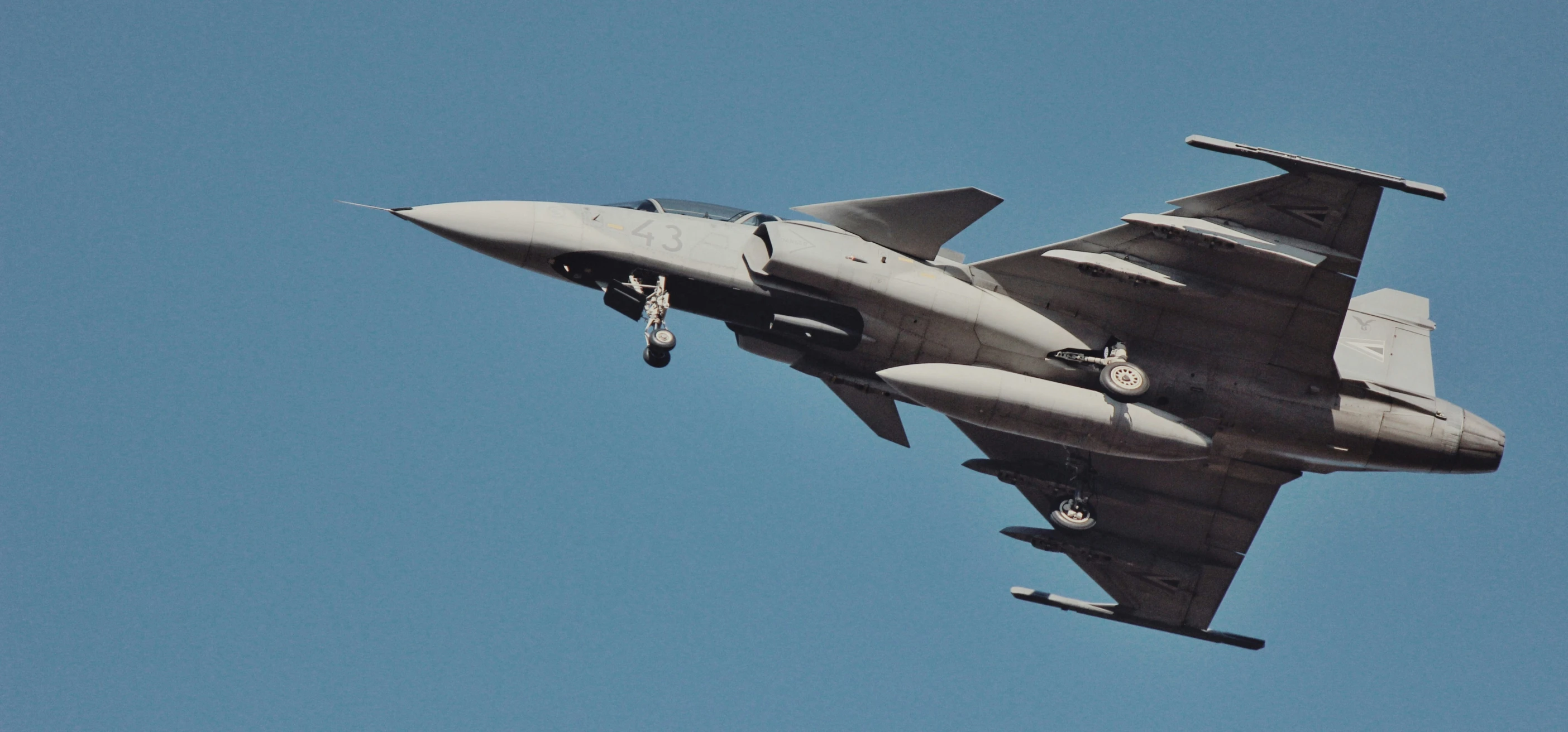 a military jet flying in the blue sky