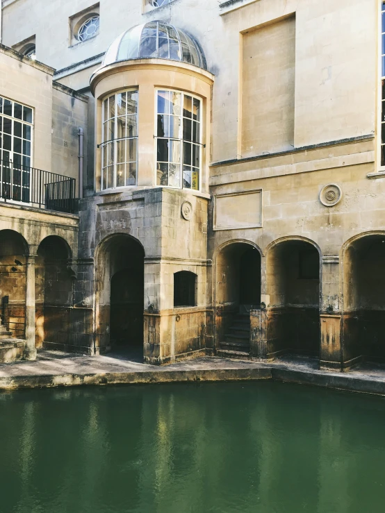 a stone and brick building with a pond behind it