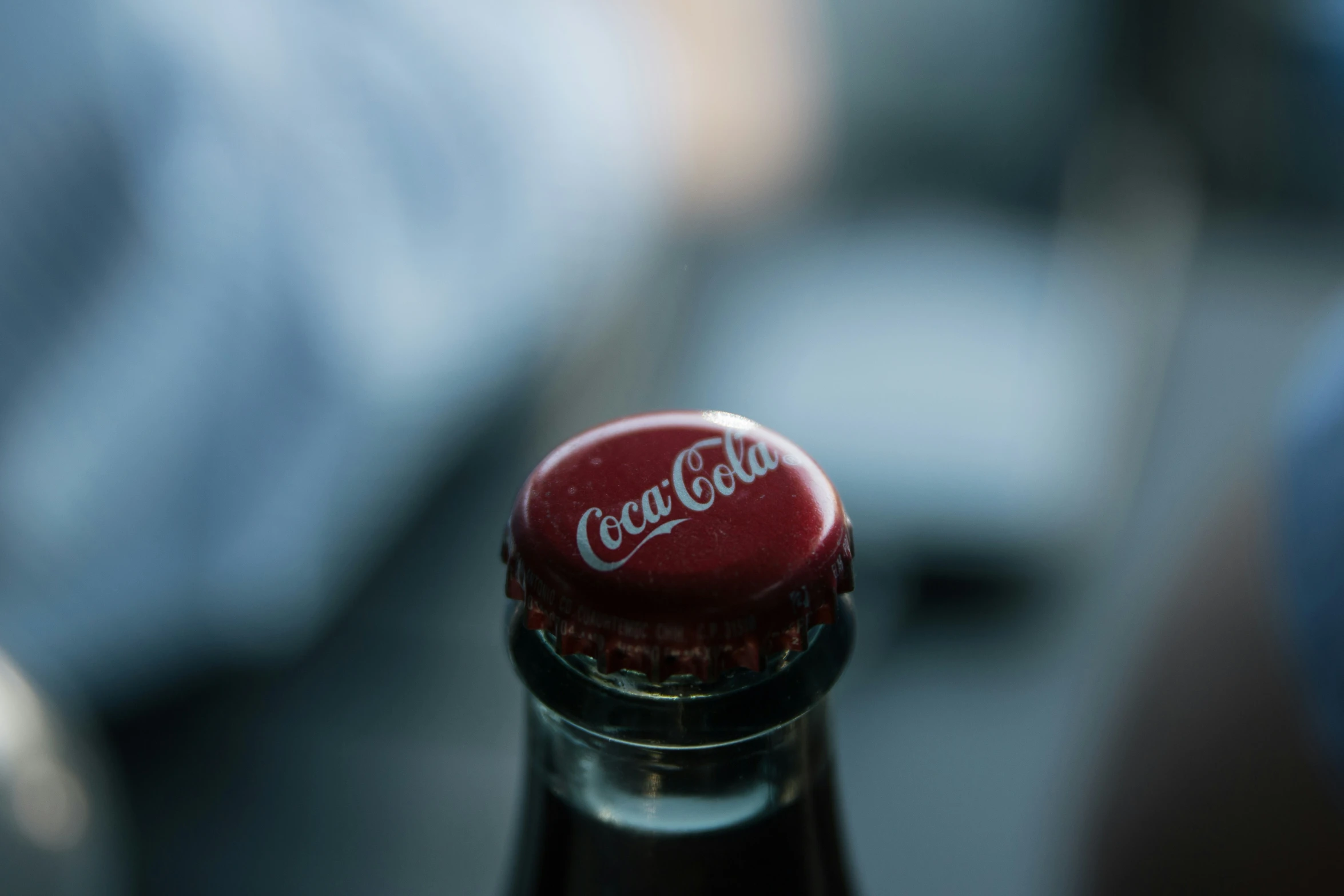 closeup of a coca - cola bottle with red cap