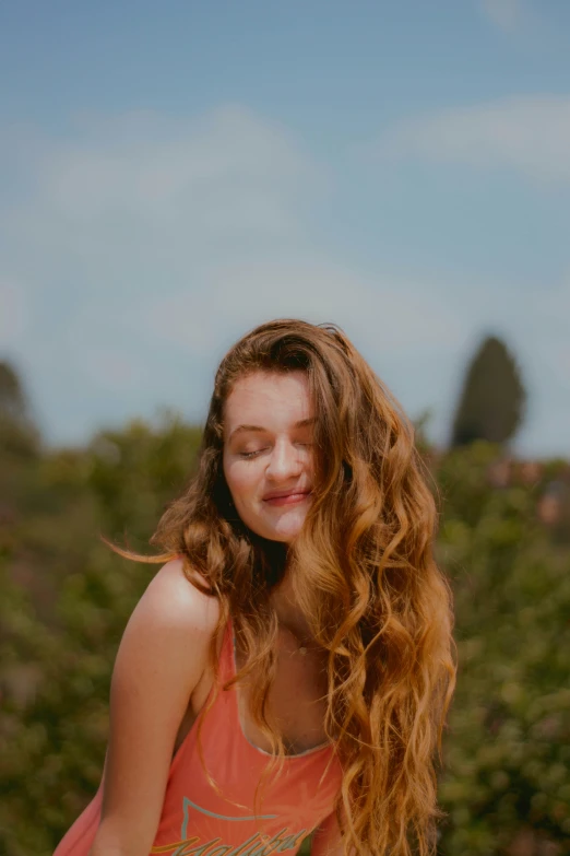 a pretty young lady standing outside with her hair blowing back