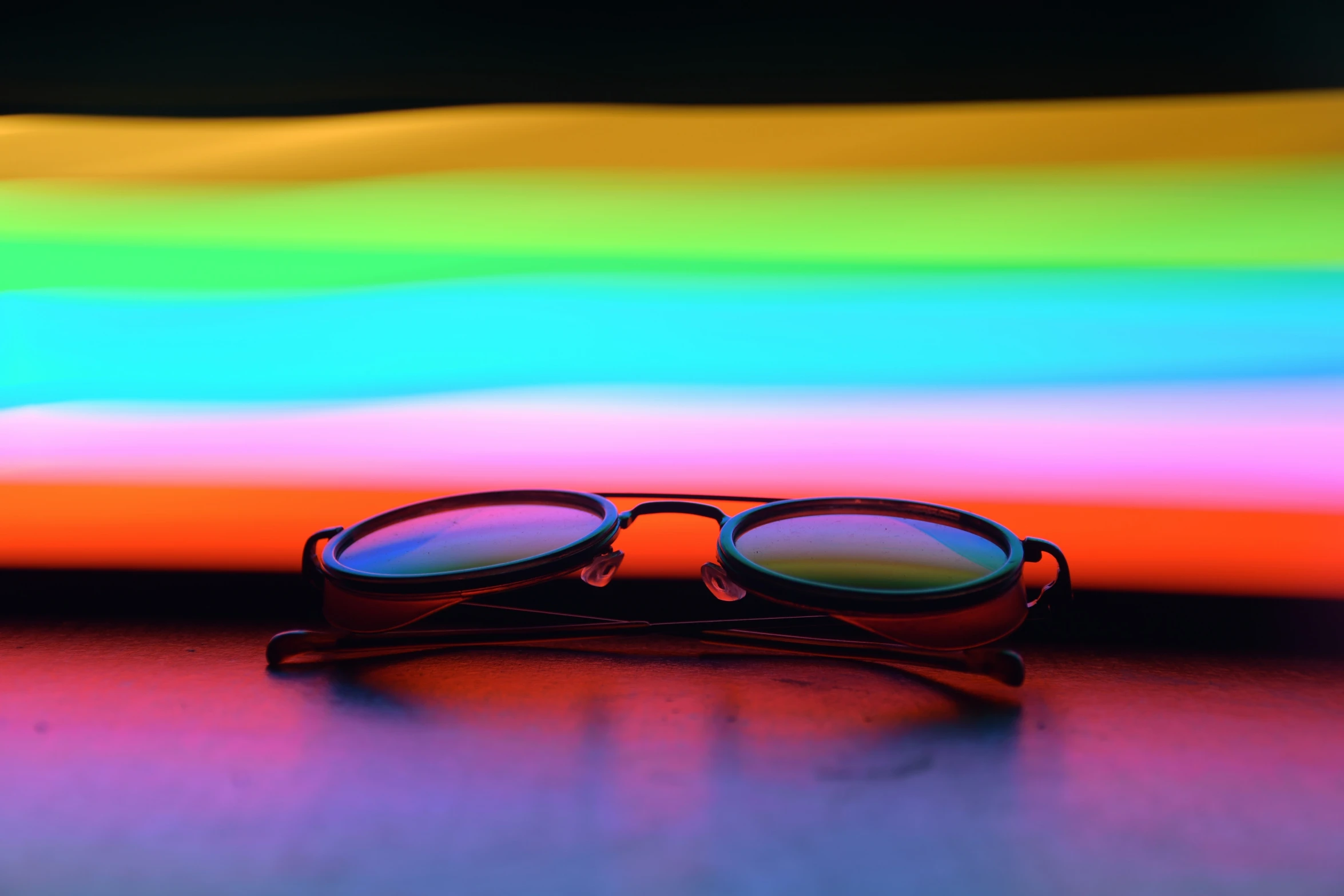 glasses resting on top of the table against a rainbow - striped background