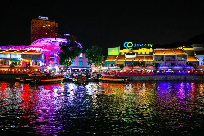 a lighted city in front of the water at night