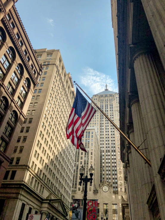 an american flag is flying high over a city street