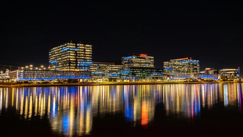 a city skyline with blue and red lights reflected on the water