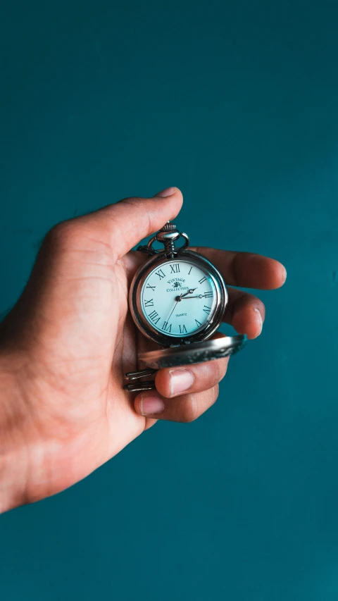 a hand that is holding an old pocket watch