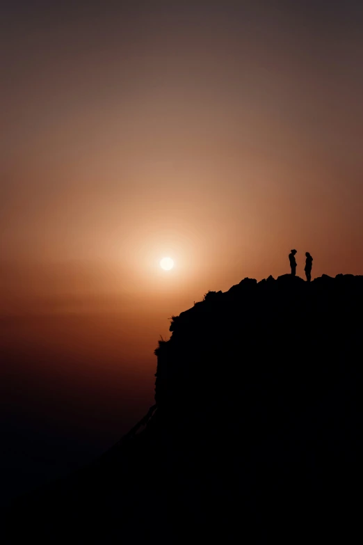 two people on top of a mountain as the sun rises