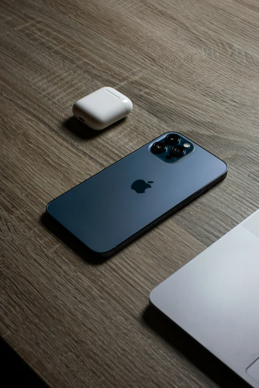 an apple mac laptop sitting next to an iphone and a mouse