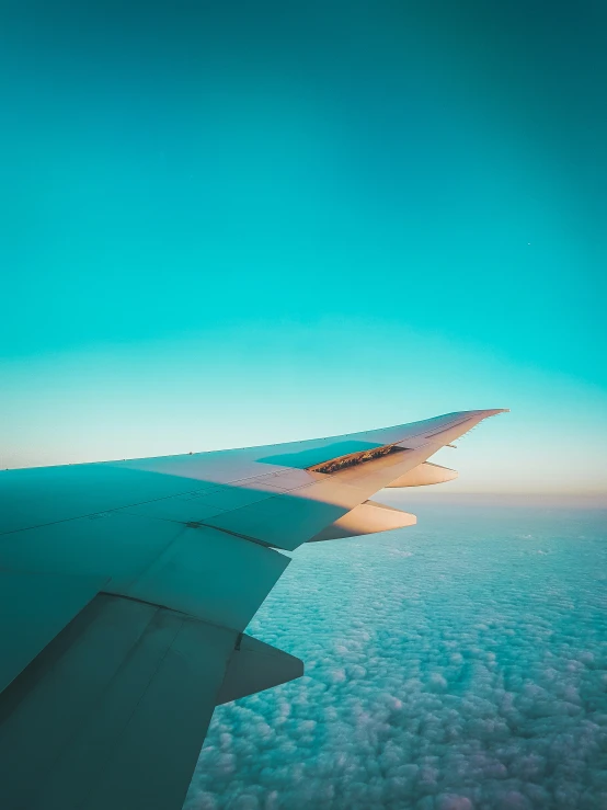 the wing of an airplane as it flies over some clouds