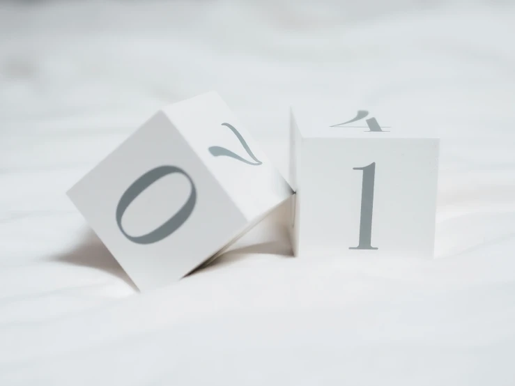 a wooden cube sitting on top of white sheets with numbers