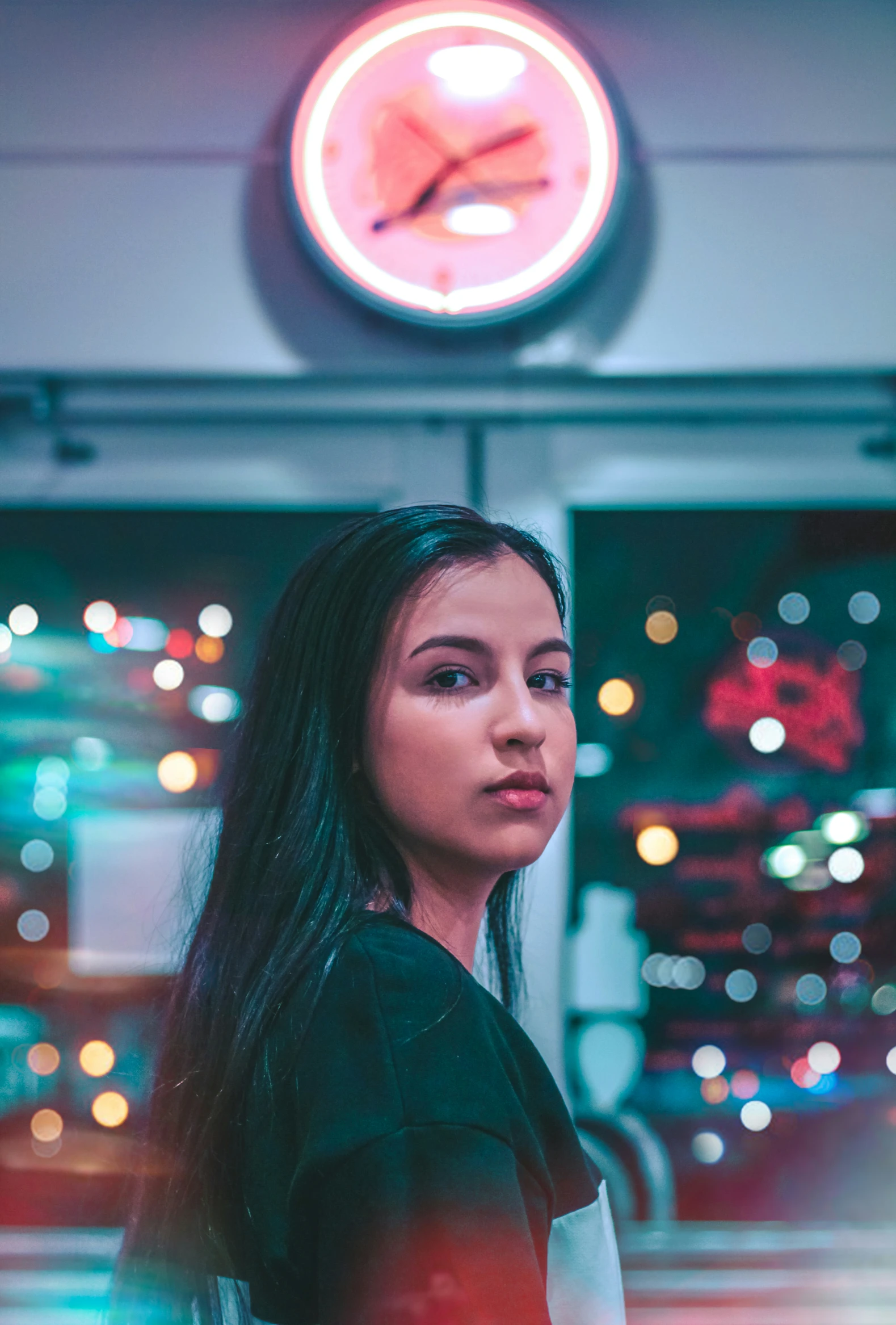 young lady in front of a lighted clock, lit neon light up buildings