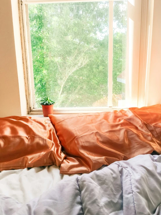 a messy bed sits near a window with green curtains