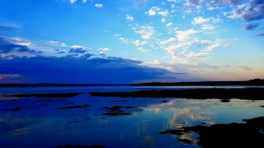 a landscape of a body of water with clouds above