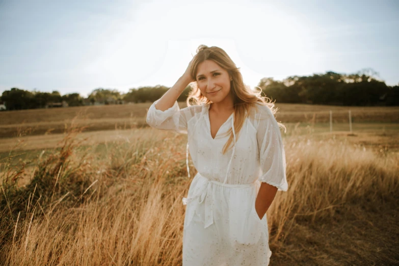 a beautiful woman standing next to tall dry grass