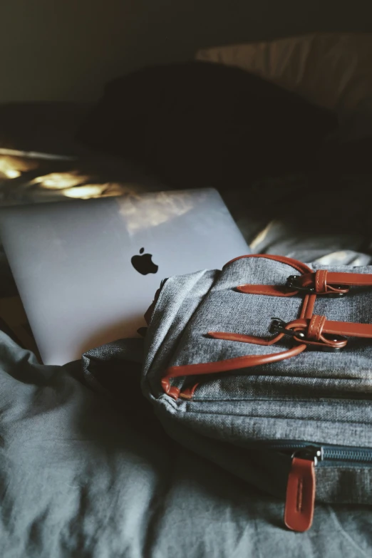 a computer is sitting on a bed next to some folded jeans