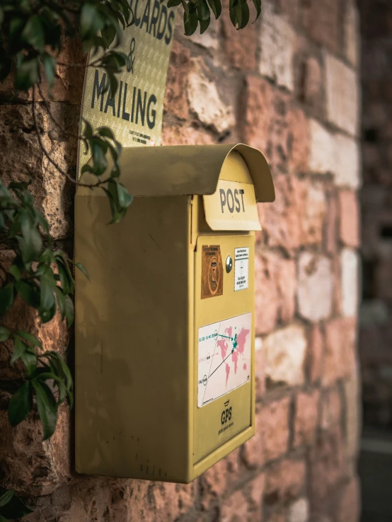 a yellow mailbox attached to a brick wall