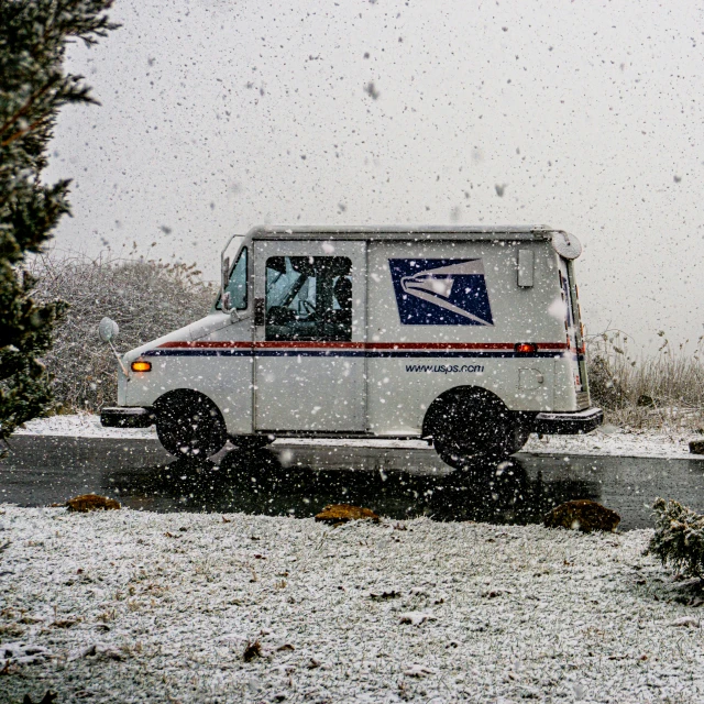 an mail truck driving through snow covered skies