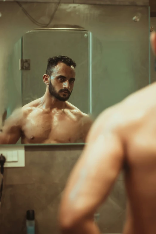 man looking into the bathroom mirror wearing his shirtless