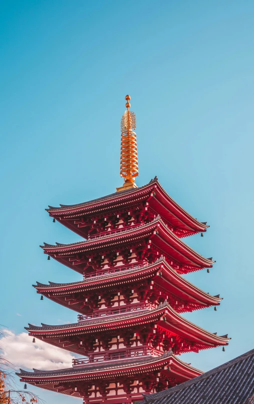 a tall red pagoda surrounded by buildings under a blue sky