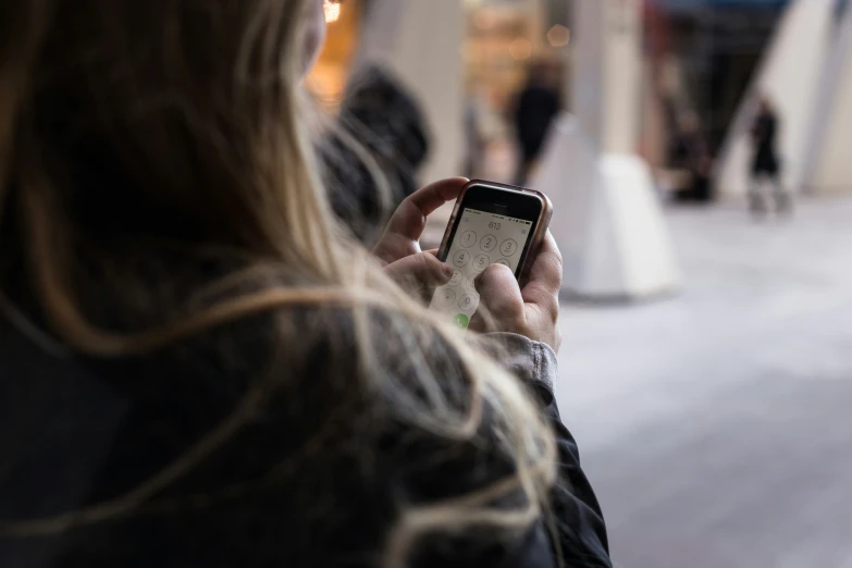 a woman in black jacket texting on a cell phone