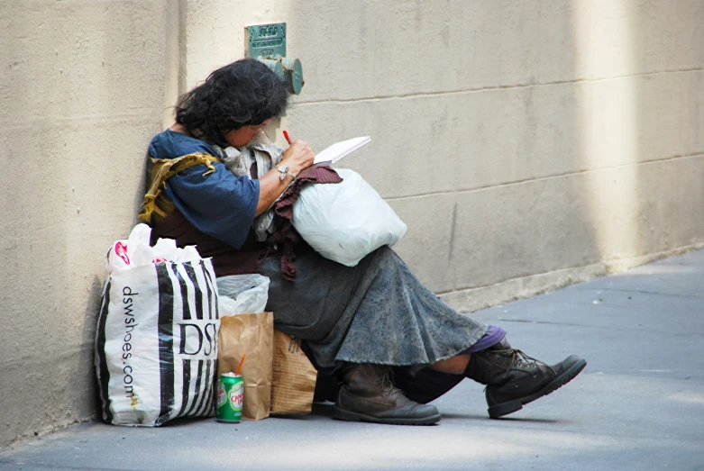 a woman sitting next to a wall holding her laptop