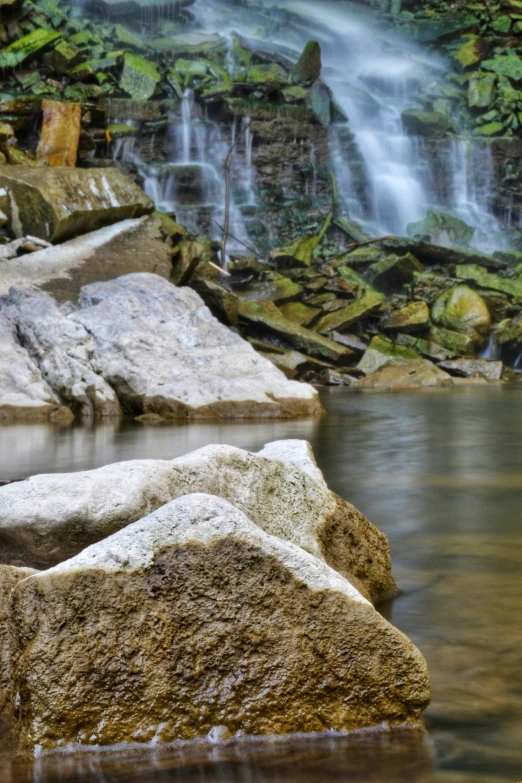 a waterfall in the middle of water with lots of rocks