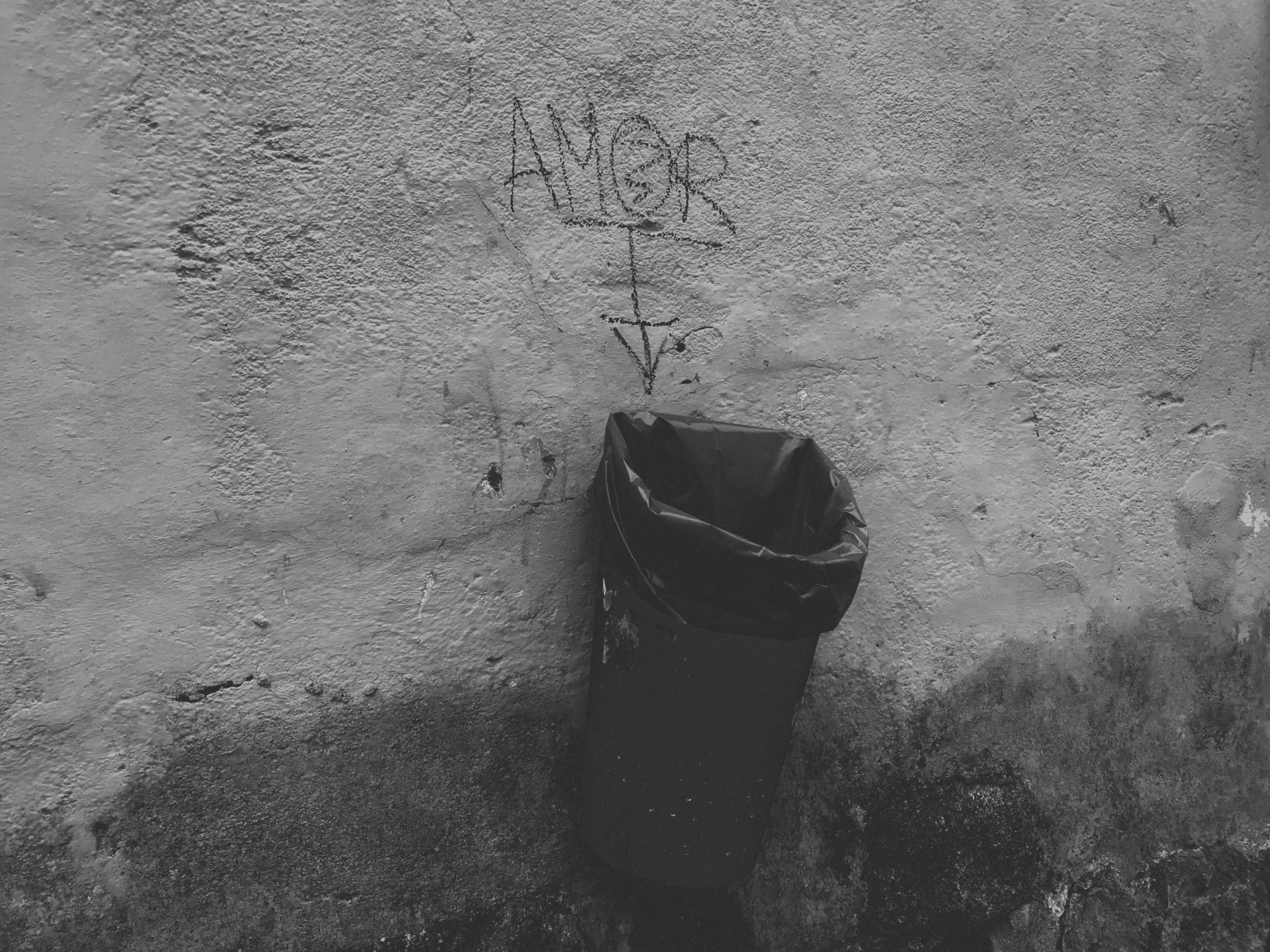 a trash can is in front of a concrete wall