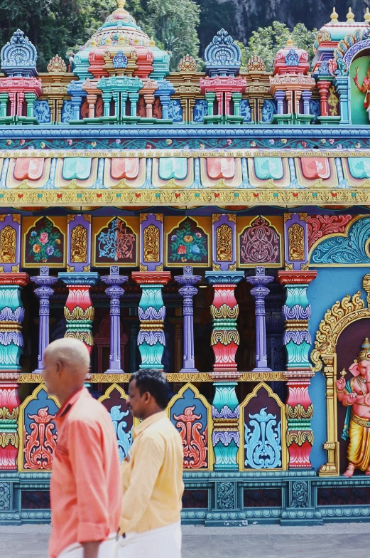 a colorful hindu temple with two men standing outside