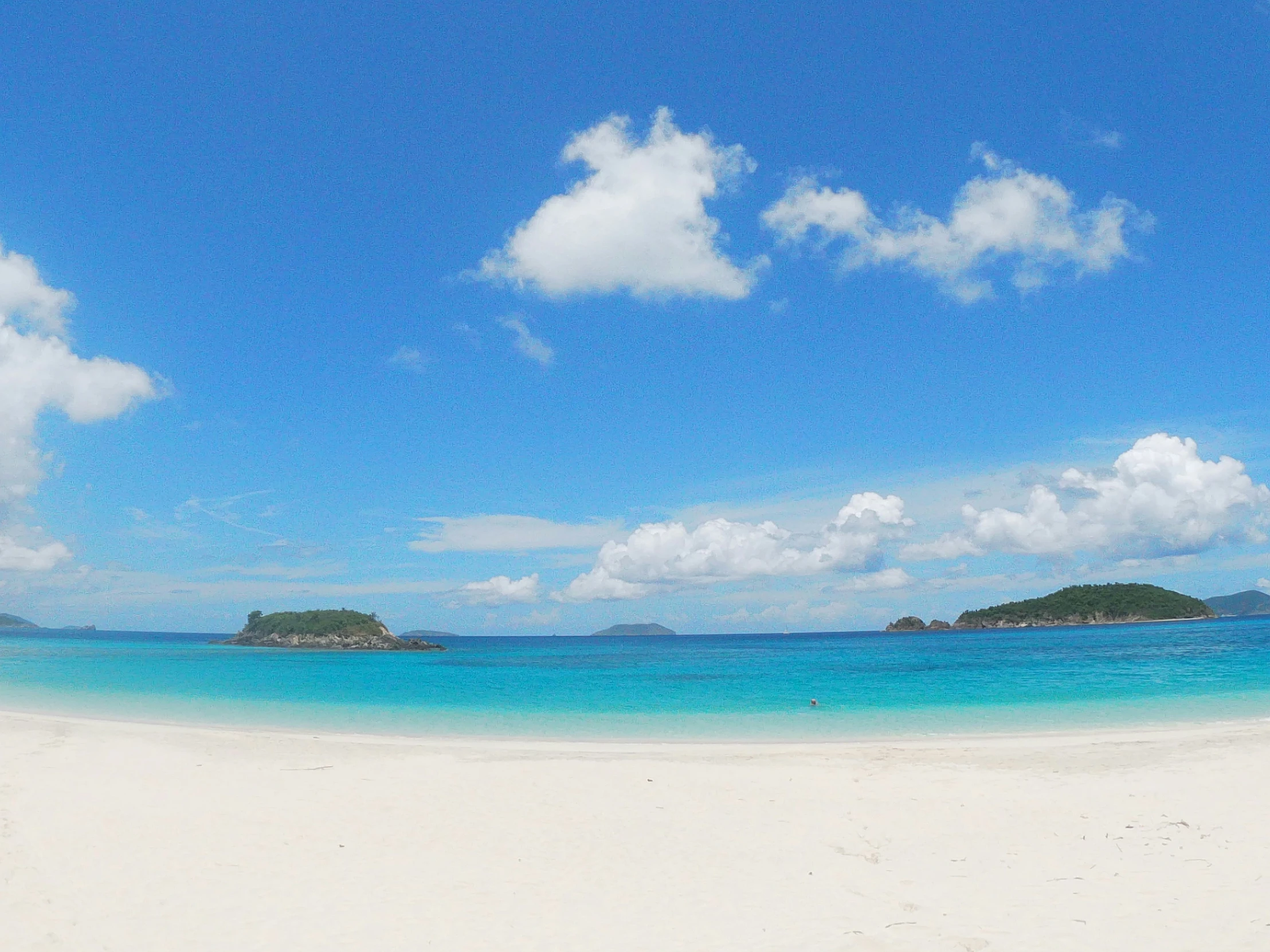 clear blue waters with many green islands in the background