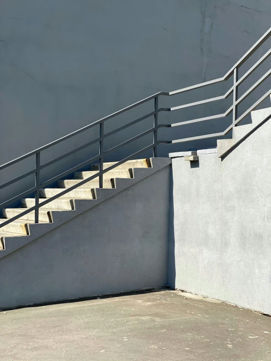 a gray wall with a staircase and railings and some steps