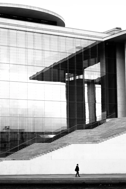 black and white pograph of someone walking past an abstract building