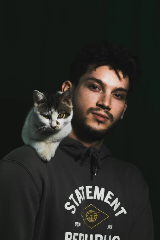 a man holds a cat on his shoulders