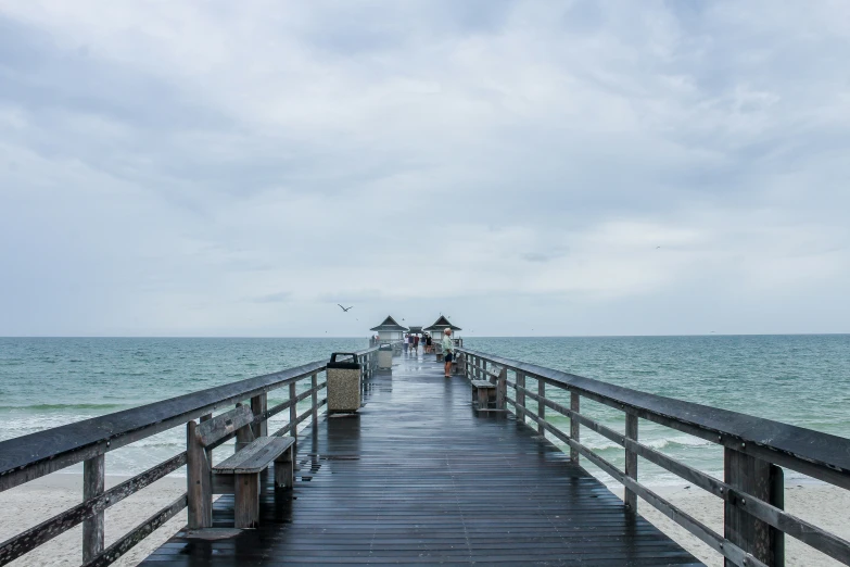 a pier on the beach with people standing on it