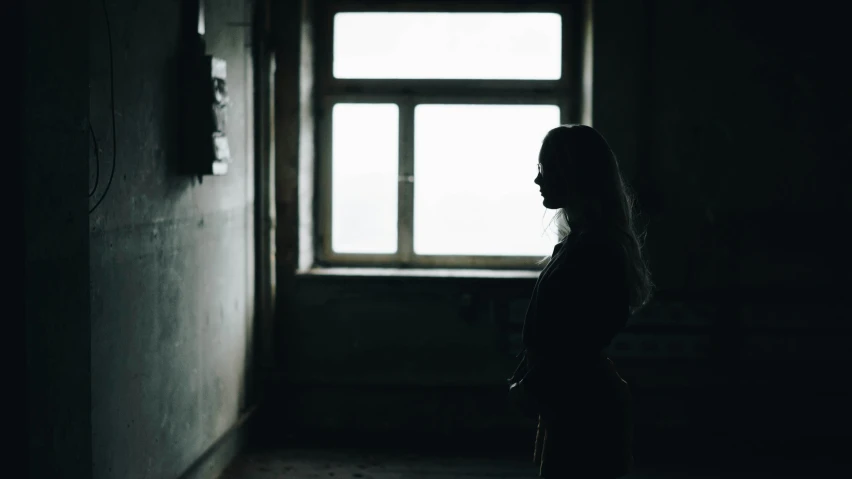 a woman stands in front of the door of an empty building