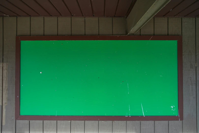 a large board on a wall with a green field in the back ground