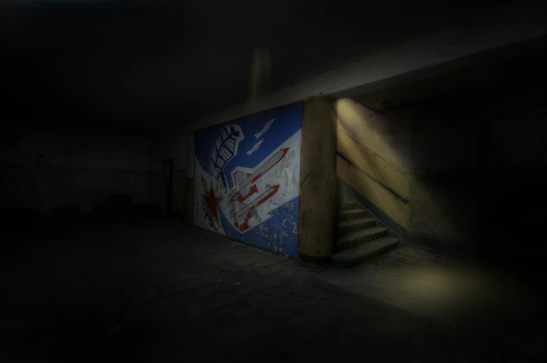 a very dark room with a graffiti wall and a stairway