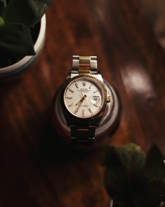a white rolex watch sitting on top of a wooden table
