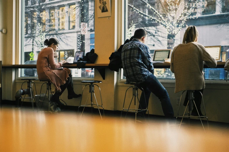 a group of people sitting at a counter with computers