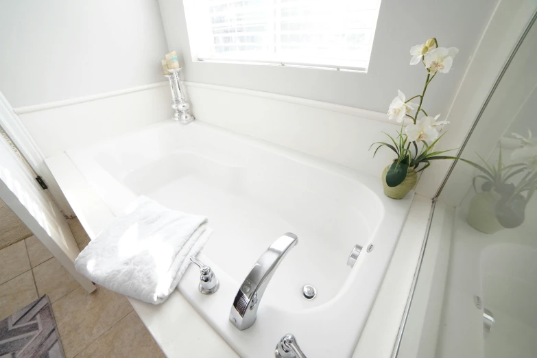 a white bathroom with a white tub and flower