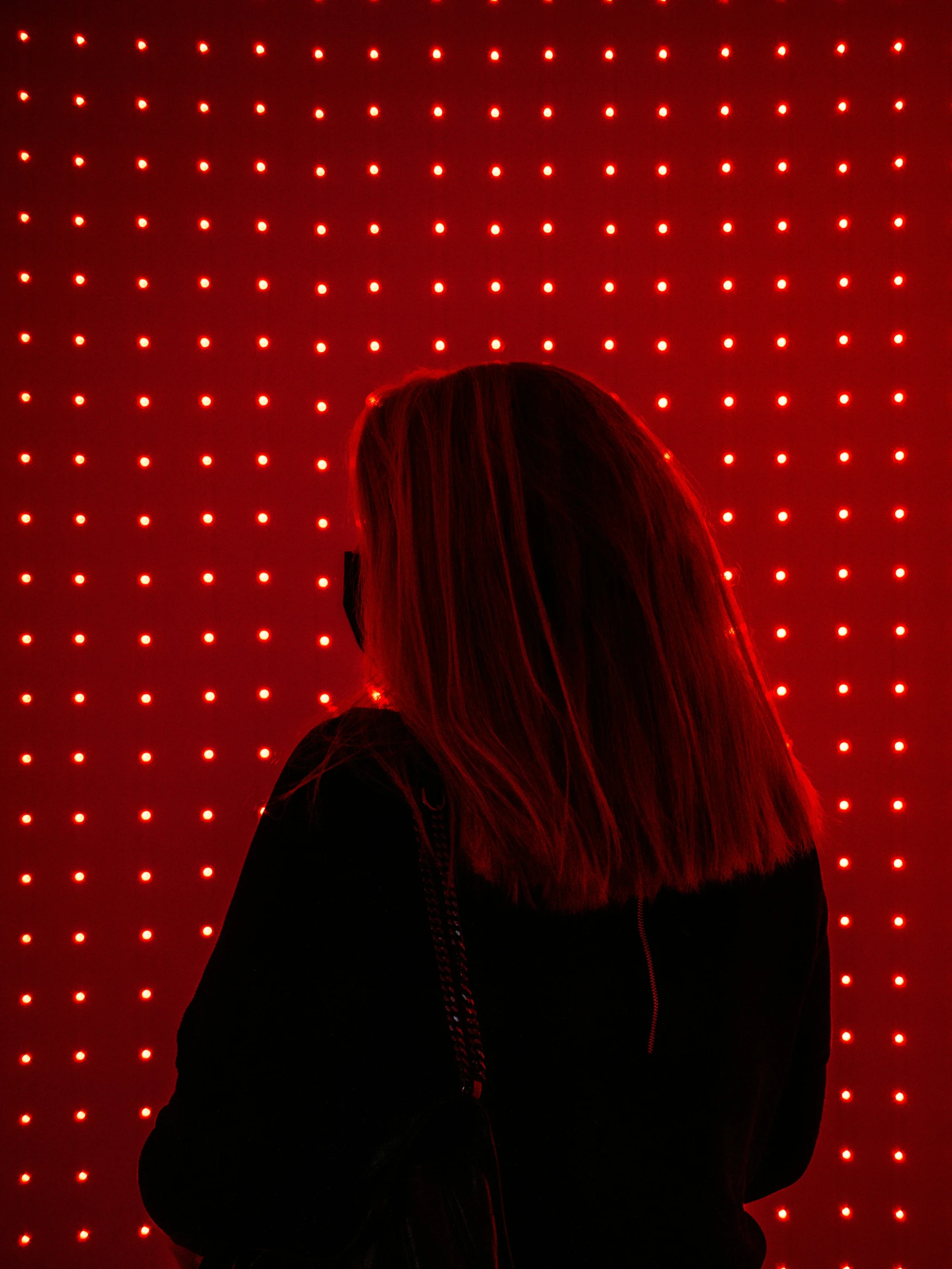 woman in front of red dot pattern wall with cell phone